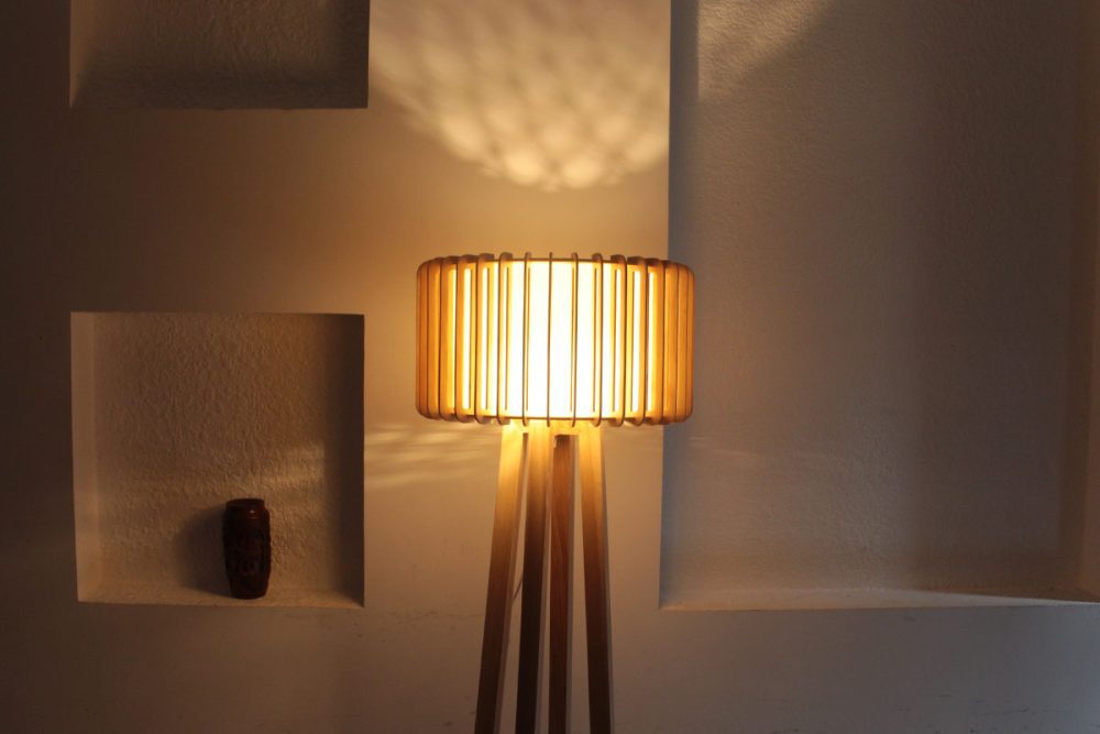 Đèn gỗ đặt sàn bốn chân trụ tròn chụp gần sau khi được thắp sáng